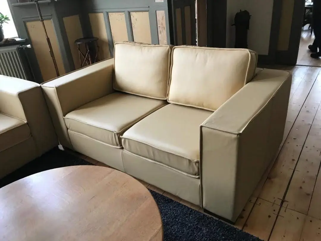 afbeelding van Leren 2-zits bank met Franse stiknaad en houten poten - geel leer