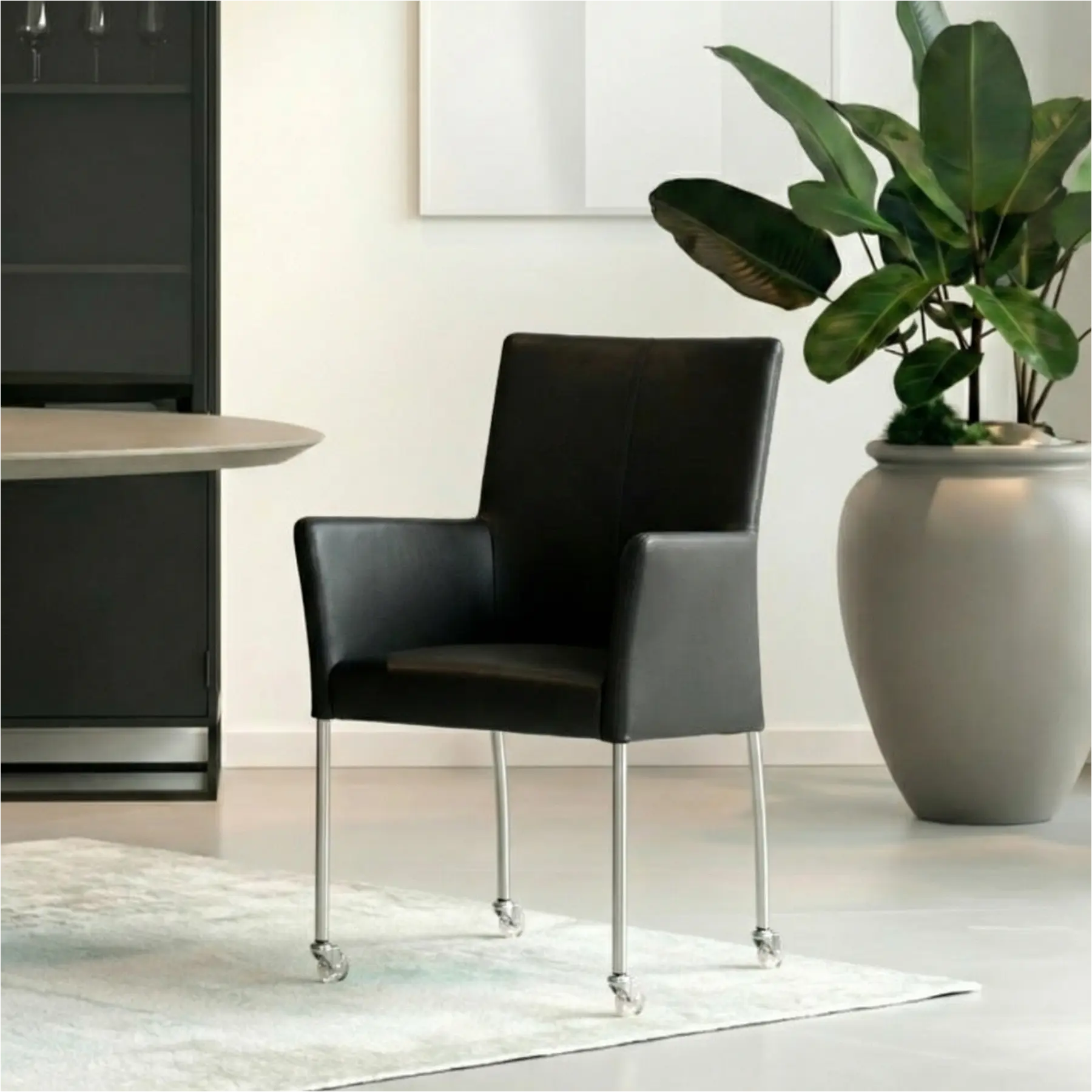 afbeelding van Leren eetkamerstoel Comfort met wieltjes en armleuning - Toledo Nero (zwart) - Poten staal rond RVS