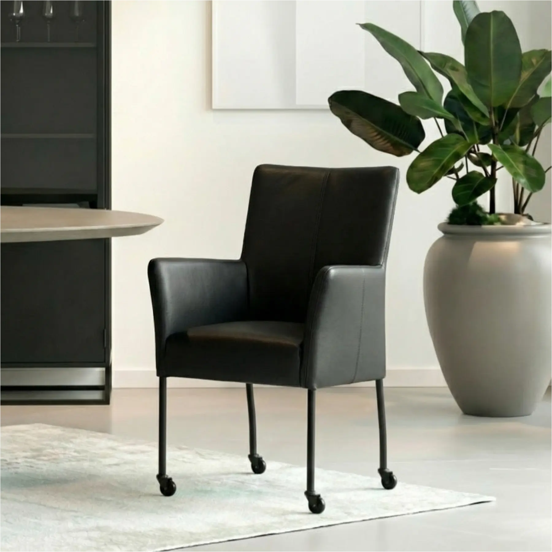 afbeelding van Leren eetkamerstoel Comfort met wieltjes en armleuning - Toledo Nero (zwart) - Poten staal rond zwart